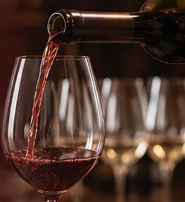 Red wine being poured into a glass at a tasting